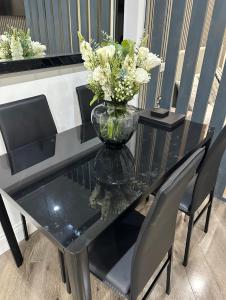 a glass table with a vase with flowers on it at Studio T in Dagenham