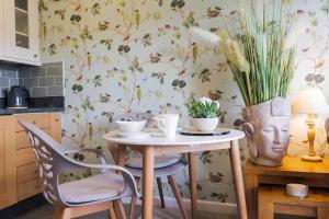 uma mesa com duas cadeiras e um vaso com flores em Serendipity ~ Romantic Hideaway in Ambleside em Ambleside