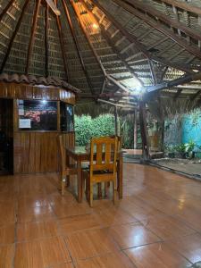 Mauras Tropical Mini Hostel & Tours في باكيرا: طاولة وكراسي يجلسون تحت سقف