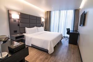 a hotel room with a white bed and a television at GHL Collection 93 in Bogotá