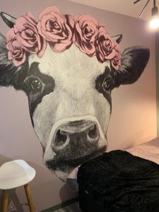 ein Wandbild einer Kuh mit Rosen auf dem Kopf in der Unterkunft Siedlisko Kępina Zdrój in Ostrów