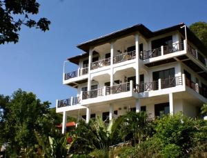 a white building with balconies and trees at Viking House Apartment in Koh Tao
