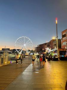 a group of people walking on a boardwalk with a ferris wheel at Studio Chaleureux au Cap d’Agde in Cap d'Agde