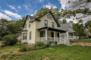 a yellow house with a porch on a lawn at Beautiful - 4bd with Contemporary Interior in Lincoln