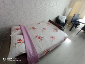 a bed with a white comforter with flowers on it at Comfortable apartment in center in Narva