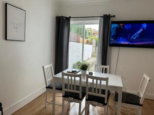 a dining room with a table and chairs and a tv at Beautiful 4 bedroom house in Enfield in Enfield Lock