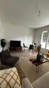 ein Wohnzimmer mit einem Sofa, einem TV und einem Tisch in der Unterkunft Beau T3 60m2 très cosy proche du centre ville in Saint-Jacques