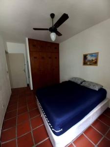 um quarto com uma cama azul e uma ventoinha de tecto em Apartamento 500M da Praia Enseada, Guarujá no Guarujá
