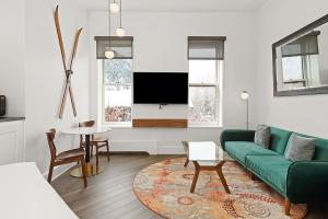 a living room with a green couch and a tv at Independence Square 202, Hotel Room Over-looking the Mall and Aspen Mountain in Aspen