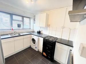 een keuken met een fornuis, een wastafel en een wasmachine bij Beautiful Modern Apt (Sleeps 5) in Croydon