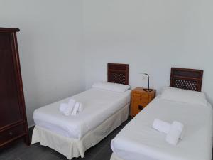2 camas en una habitación con sábanas blancas y toallas en Duplex La Graciosa en Caleta de Sebo