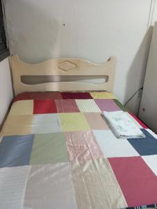 Una cama en una habitación con una colcha colorida. en Cortiço da Lapa, en Río de Janeiro