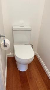 a white toilet in a bathroom with a wooden floor at Melbourne Inner City Holiday Home Near CBD & Flemington in Melbourne