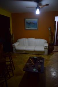 ein Wohnzimmer mit einem weißen Sofa und einem Tisch in der Unterkunft Casa Verde do Peró in Cabo Frio