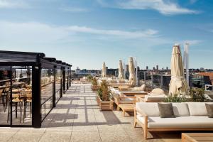 a rooftop patio with tables and chairs and umbrellas at NH Collection Copenhagen in Copenhagen