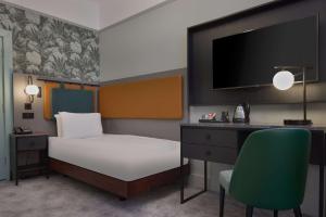 a bedroom with a bed and a desk and a tv at DoubleTree By Hilton Brighton Metropole in Brighton & Hove