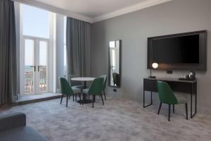 a living room with a table and chairs and a television at DoubleTree By Hilton Brighton Metropole in Brighton & Hove