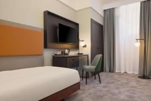 a hotel room with a bed and a desk and a television at DoubleTree By Hilton Brighton Metropole in Brighton & Hove