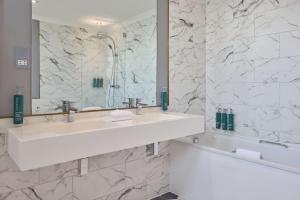 a white bathroom with a sink and a tub at DoubleTree By Hilton Brighton Metropole in Brighton & Hove