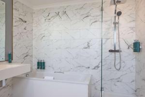a bathroom with a shower with a tub and a sink at DoubleTree By Hilton Brighton Metropole in Brighton & Hove