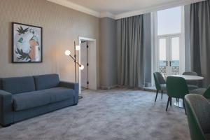 a living room with a blue couch and a table at DoubleTree By Hilton Brighton Metropole in Brighton & Hove