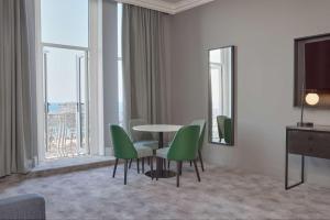 a dining room with a table and green chairs at DoubleTree By Hilton Brighton Metropole in Brighton & Hove