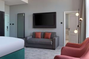 a bedroom with a bed and a couch and a tv at DoubleTree By Hilton Brighton Metropole in Brighton & Hove