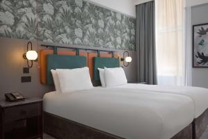 a large white bed in a room with a wall at DoubleTree By Hilton Brighton Metropole in Brighton & Hove