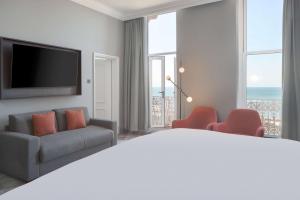 a hotel room with a bed and chairs and a television at DoubleTree By Hilton Brighton Metropole in Brighton & Hove