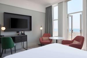 a hotel room with a bed and chairs and a television at DoubleTree By Hilton Brighton Metropole in Brighton & Hove