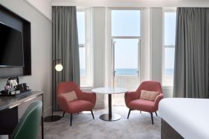 a hotel room with two chairs and a table and windows at DoubleTree By Hilton Brighton Metropole in Brighton & Hove