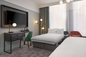 a hotel room with a bed and a desk and a tv at DoubleTree By Hilton Brighton Metropole in Brighton & Hove