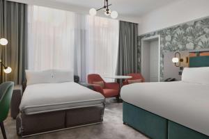 a hotel room with two beds and a chair at DoubleTree By Hilton Brighton Metropole in Brighton & Hove