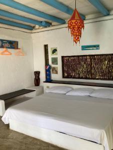 um quarto com uma grande cama branca e um lustre em Isla Única em Isla Grande