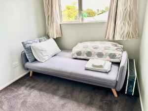 a small couch in a room with a window at Albany Modern Private 2 bedroom 2 bathroom with Full Kitchen Netflix in Auckland