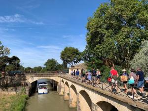 people walking on a bridge over a river with a boat at Studio Chaleureux au Cap d’Agde in Cap d'Agde