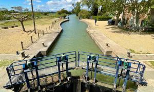 a canal with a blue railing next to a river at Studio Chaleureux au Cap d’Agde in Cap d'Agde