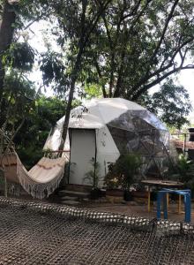 a white tent with a hammock in a yard at Hotel Ambrosia Lodge in Rivera