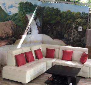 a white couch with red pillows in front of a mural at Hotel Ambrosia Lodge in Rivera