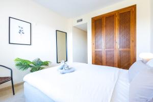 um quarto com uma cama branca com uma toalha em Top floor spacious apartment with sea views in Costalita em Estepona