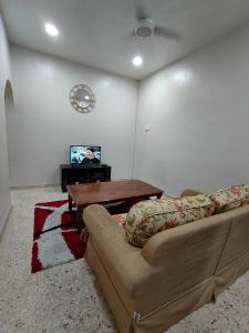 sala de estar con sofá, mesa y TV en Homestay Melaka Baitul Saadah en Melaka