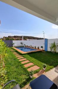 un patio trasero con piscina y césped en Chalet villa QUE POUR LES FAMILLES en Imouzzer Kandar