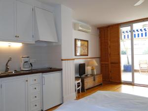 a kitchen with white cabinets and a tv in a room at Antonio's Apartment in Sitges