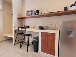 a kitchen with a bar with stools and a sink at Xaman - Boutique Studios in Cancún