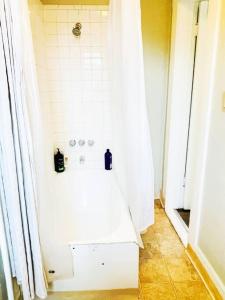 a bathroom with a shower with a white tiled wall at #6 Studio/ Downtown San Jose/Parking/laundry/SJSU in San Jose