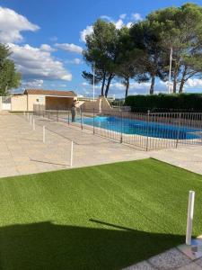 Appartement «Marrakech » à Avignon في أفينيون: سور مع حديقة خضراء بجوار حمام سباحة
