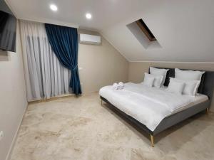 a bedroom with a large white bed with blue curtains at Sika Palladium Central Apartment in Arad