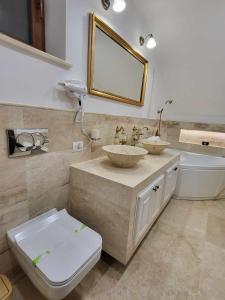 a bathroom with two sinks and a toilet and a mirror at Sika Palladium Central Apartment in Arad