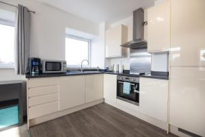 a kitchen with white cabinets and a microwave at Entire 1 Bed - No. 45 - Free Parking - The Cosy Collection Ltd in York
