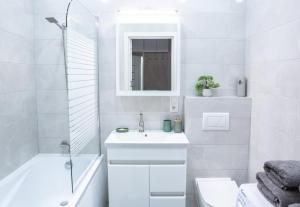 a white bathroom with a sink and a mirror at Spacious Living- Free Coffee, Netflix & More! in Chişinău
